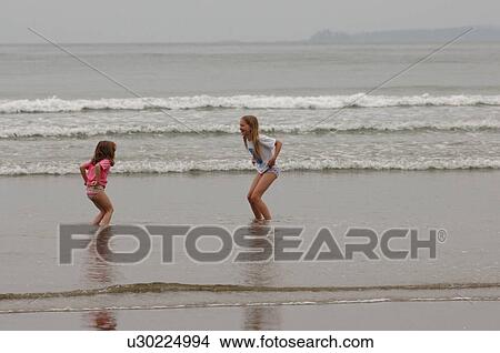Two girls playing on ocean beach, Wickaninnish Beach, Vancouver Island, Canada View Large Photo Image Picture - Two girls playing on ocean beach, Wickaninnish Beach, Vancouver Island, Canada. Fotosearch