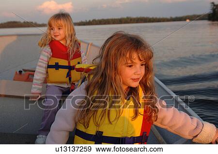 Two girls sitting in a boat View Large Photo Image Stock Photo - Two girls sitting in a boat. Fotosearch