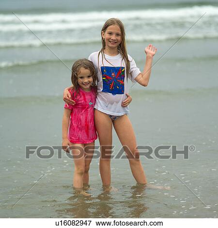 Two girls standing in water on beach, Wickaninnish Beach Trail, Vancouver Island, Canada View Large Photo Image Stock Photo - Two girls standing in water on beach, Wickaninnish Beach Trail, Vancouver Island, Canada. Fotosearch