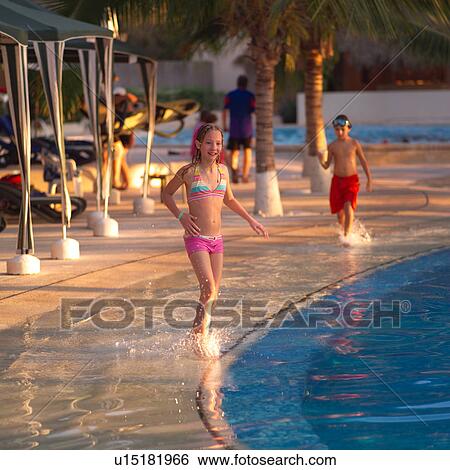 Stock Photograph - Young girl walking on edge of pool. Fotosearch