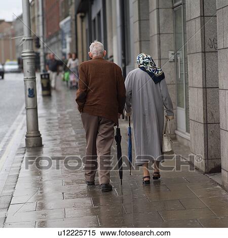 Dublin, Ireland - Man and Woman walking with umbrellas View Large Photo Image Stock Photography - Dublin, Ireland - Man and Woman walking with umbrellas. Fotosearch