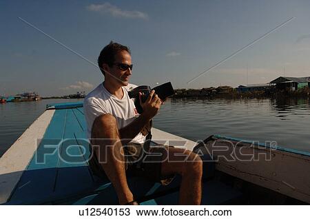 Male tourist taking pictures on a boat in Cambodia View Large Photo Image Stock Image - Male tourist taking pictures on a boat in Cambodia. Fotosearch