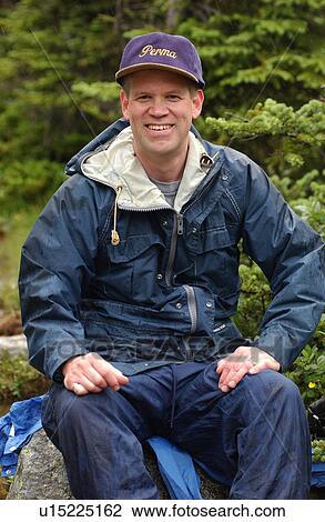 Man sitting on a rock in the forest, Rocky Mountains, Canada View Large Photo Image Stock Image - Man sitting on a rock in the forest, Rocky Mountains, Canada. Fotosearch