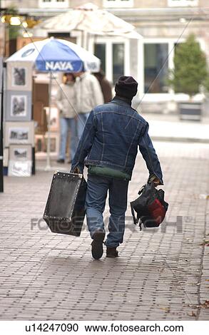 Rear view of young man walking with luggage on the streets of Montreal, Canada View Large Photo Image Stock Image - Rear view of young man walking with luggage on the streets of Montreal, Canada. Fotosearch