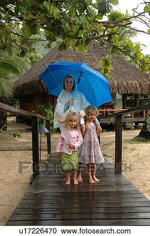 A young mother holding an umbrella standing with her two young daughters View Large Photo Image Stock Image - A young mother holding an umbrella standing with her two young daughters. Fotosearch