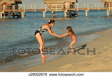 A young woman playing with her daughter (6-8) on a beach View Large Photo Image Stock Photo - A young woman playing with her daughter (6-8) on a beach. Fotosearch