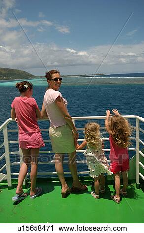 Stock Image - A young woman standing with three young girls (5-15) on a boat. Fotosearch