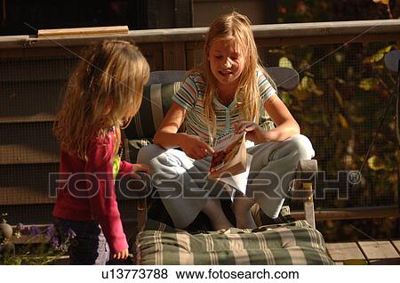 Child sitting in lounge chair pointing at a book View Large Photo Image Stock Photo - Child sitting in lounge chair pointing at a book. Fotosearch