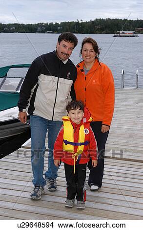 Portrait of a young couple and their son walking on a pier View Large Photo Image Picture - Portrait of a young couple and their son walking on a pier. Fotosearch