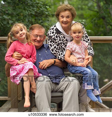 Stock Photograph - Portrait of grandparents with their granddaughters sitting on their laps. Fotosearch
