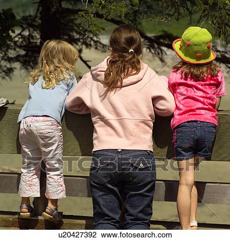 Three girls looking over a fence View Large Photo Image Stock Image - Three girls looking over a fence. Fotosearch