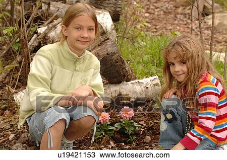 Two girls by flowers in a garden View Large Photo Image Stock Image - Two girls by flowers in a garden. Fotosearch