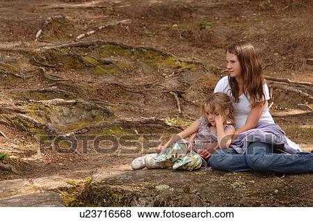 Two girls sitting on a rock View Large Photo Image Stock Photo - Two girls sitting on a rock. Fotosearch