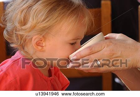 Close-up of a young girl (2-4) drinking from a cup held by a woman View Large Photo Image Stock Photograph - Close-up of a young girl (2-4) drinking from a cup held by a woman. Fotosearch