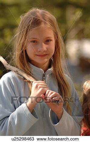 Stock Image - Close up of blonde girl holding a stick over her shoulder. Fotosearch