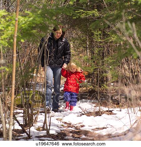Stock Photograph - Mother and daughter walking in the woods holding hands. Fotosearch