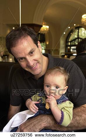 Stock Photograph - Portrait of young man holding a baby in Prague. Fotosearch