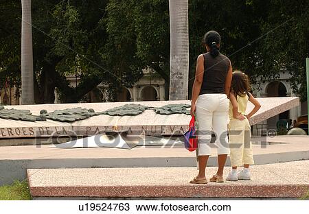 Stock Image - Rear view of a mother and daughter looking at a memorial. Fotosearch