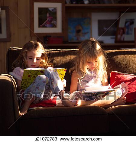 Two girls on a sofa looking at books View Large Photo Image Stock Image - Two girls on a sofa looking at books. Fotosearch