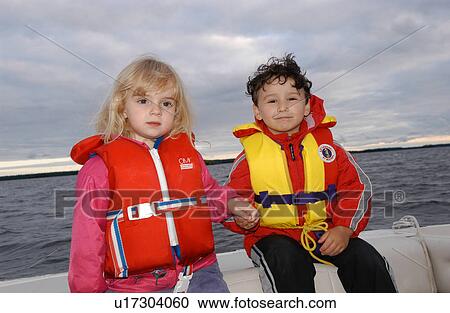 Two young children in life jackets sitting on the side of a motorboat View Large Photo Image Stock Image - Two young children in life jackets sitting on the side of a motorboat. Fotosearch