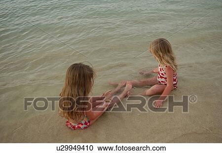 Stock Image - Two young girls (6-8) playing in water. Fotosearch