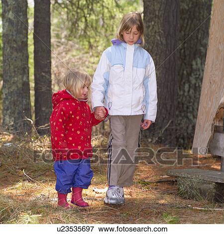 Stock Photo - Two young girls holding hands walking in the woods. Fotosearch