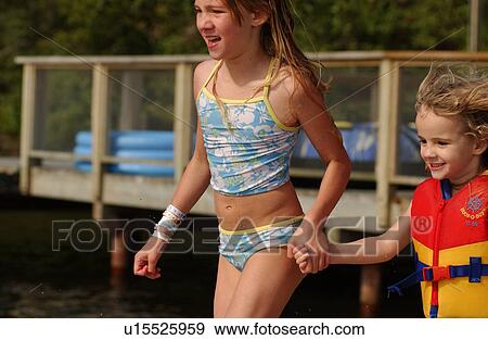 Two young girls holding hands wearing swimming gear View Large Photo Image Stock Photo - Two young girls holding hands wearing swimming gear. Fotosearch