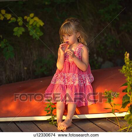 Picture - 4 year old sitting on overturned canoe. Fotosearch