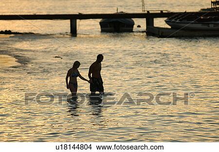 A young couple wading into the sea, Moorea, Tahiti, French Polynesia, South Pacific View Large Photo Image Picture - A young couple wading into the sea, Moorea, Tahiti, French Polynesia, South Pacific. Fotosearch
