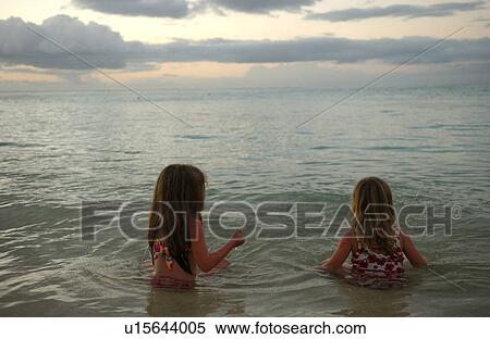 Stock Photography - Two young girls (6-8) playing in water. Fotosearch