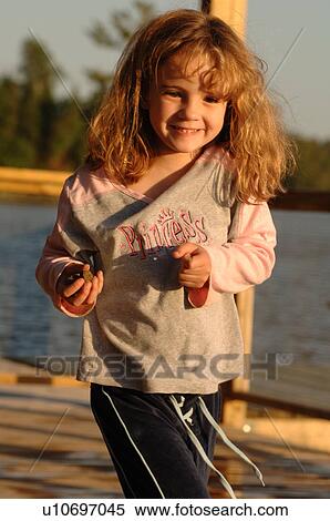 Stock Photography - Young girl holding an object in her hand. Fotosearch