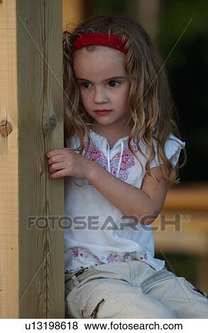 Young girl sitting leaning against a wooden pole View Large Photo Image Stock Photo - Young girl sitting leaning against a wooden pole. Fotosearch