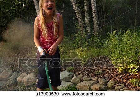 Stock Image - Young girl standing outdoors laughing. Fotosearch