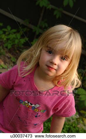 Stock Image - Young girl standing outdoors looking at camera. Fotosearch