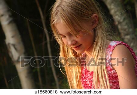 Young girl standing outdoors looking down View Large Photo Image Stock Photo - Young girl standing outdoors looking down. Fotosearch