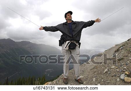 Close-up of a man standing on top of a mountain with his arms spread out View Large Photo Image Stock Image - Close-up of a man standing on top of a mountain with his arms spread out. Fotosearch