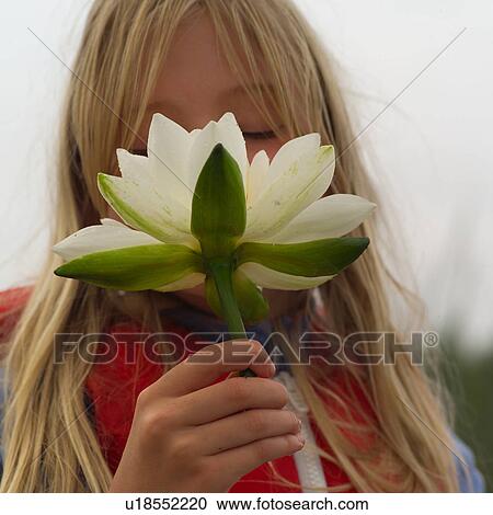Close-up of a young girl smelling a lotus View Large Photo Image Stock Image - Close-up of a young girl smelling a lotus. Fotosearch