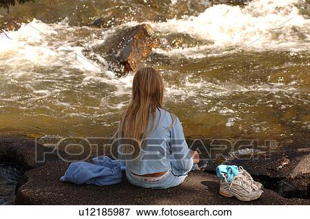 Girl sitting at edge of river View Large Photo Image Stock Photo - Girl sitting at edge of river. Fotosearch