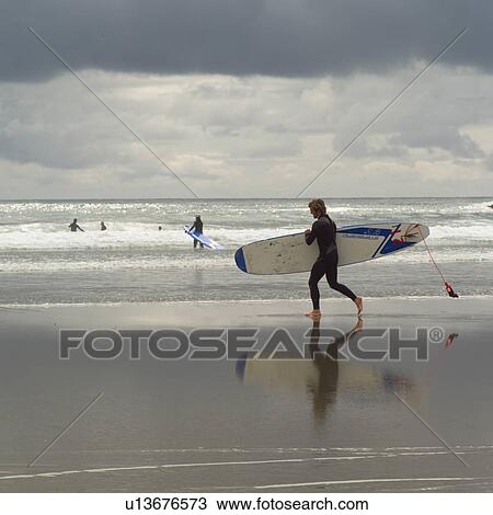 Surfer with surfboard on beach View Large Photo Image Stock Image - Surfer with surfboard on beach. Fotosearch
