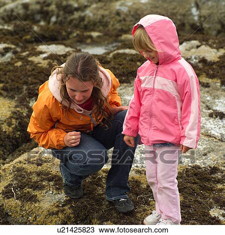 Stock Image - Two girls looking towards the ground. Fotosearch