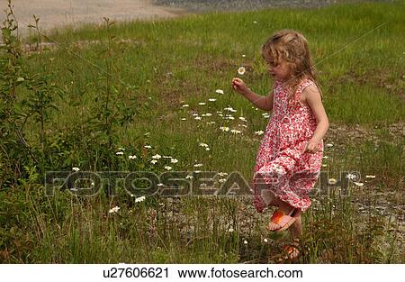 Young girl holding a flower in her hand walking View Large Photo Image Stock Image - Young girl holding a flower in her hand walking. Fotosearch