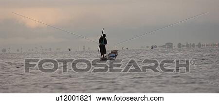 Stock Image - Man rowing along lake. Fotosearch