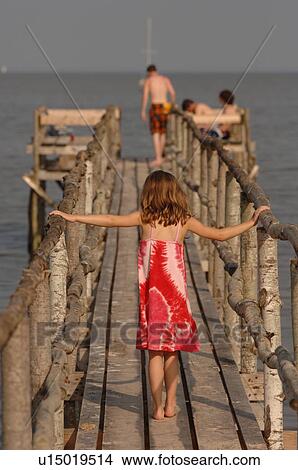 Picture - 5 year old girl walking on wooden pier. Fotosearch