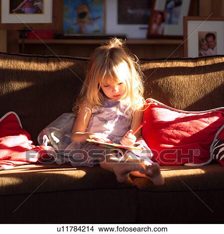 5 year old sitting on a sofa and writing in a book View Large Photo Image Picture - 5 year old sitting on a sofa and writing in a book. Fotosearch