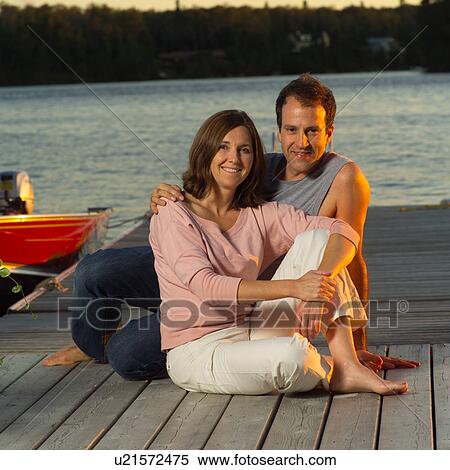 Stock Photography - Couple sitting on dock. Fotosearch