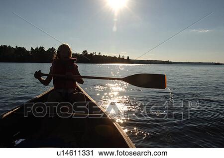 Stock Image - Silhouette of a woman holding an oar. Fotosearch