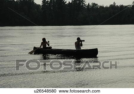Stock Image - Silhouette of canoe on lake. Fotosearch