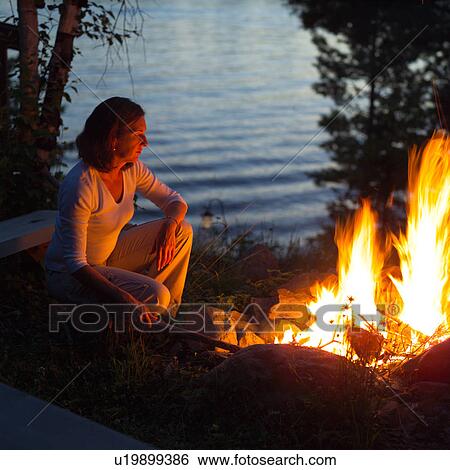 Stock Photograph - Woman sitting by fire. Fotosearch