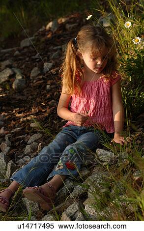 Stock Photography - Young girl sitting on rocks outdoors. Fotosearch