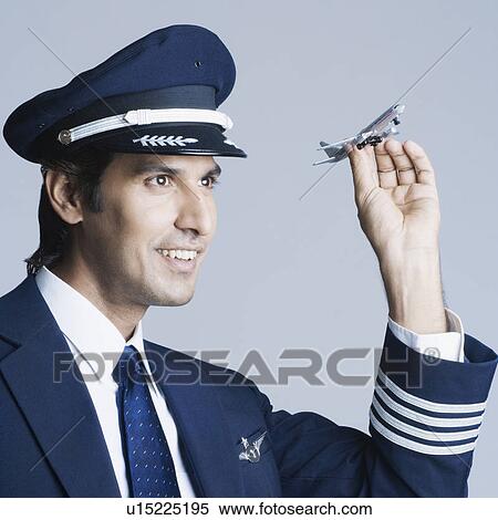Stock Photography - Close-up of a pilot holding a toy airplane and smiling. Fotosearch